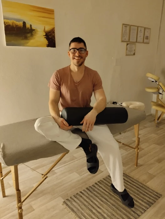 Martin Hála, masér, sedí na masážním lehátku s masážním válcem